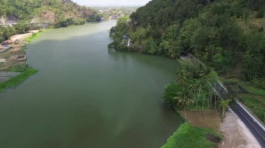 Serayu nehri ve yeşil ormandaki ağaçlar arasındaki otoyolun 4k hava aracı görüntüsü