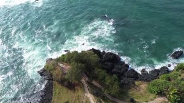 İnsansız hava aracı manzarası Menganti Sahili, Kebumen, Central Java, Endonezya, sakin deniz dalgaları, mercan kayalıkları ve yeşil ağaçlarla dolu bir sahil.