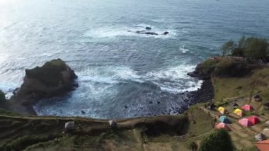 İnsansız hava aracı manzarası Menganti Sahili, Kebumen, Central Java, Endonezya, sakin deniz dalgaları, mercan kayalıkları ve yeşil ağaçlarla dolu bir sahil.