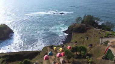 Menganti Sahili, Kebumen, Central Java, Endonezya Sahili sakin deniz dalgaları, mercan kayalıkları, yeşil ağaçlar ve birkaç kamp çadırıyla