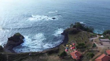 Menganti Sahili, Kebumen, Central Java, Endonezya Sahili sakin deniz dalgaları, mercan kayalıkları, yeşil ağaçlar ve birkaç kamp çadırıyla