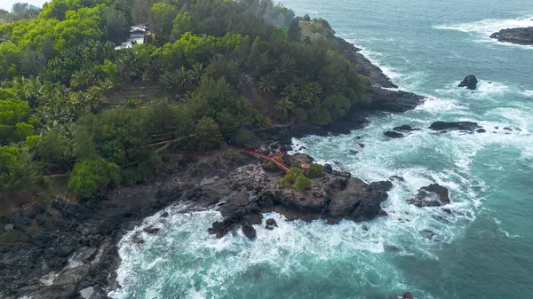 Menganti Sahili, Kebumen, Central Java, Endonezya 'nın insansız hava aracı manzarası, beyaz kum, sakin dalgalar, mercan kayalıkları ve yeşil ağaçlarla dolu güzel sahil.