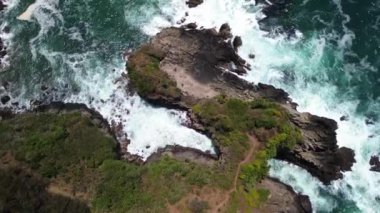 İnsansız hava aracı manzarası Gebyuran Sahili 'ndeki Tanjung Karang Gelini, Kebumen, Merkezi Java, Endonezya, güzel mercan kayalıkları, sakin dalgaları, tepeleri ve yeşil ağaçları olan bir sahil.