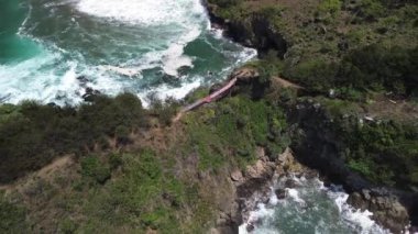 Gebyuran Sahili 'ndeki Tanjung Karang Penganten, Kebumen, Central Java, Endonezya' daki bambu köprüsünün insansız hava aracı görüntüsü, güzel mercan kayalıkları, sakin dalgalar, tepeler ve yeşil ağaçlar.