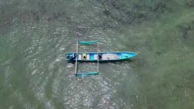 Beyaz kum, sakin dalgalar, uçurumlar ve yeşil ağaçlarla Menganti sahilinin insansız hava aracı görüntüsü ve geleneksel balıkçıların ve balıkçı teknelerinin faaliyetleri