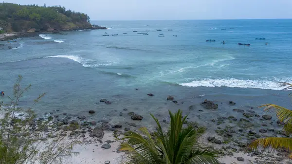 İnsansız hava aracı manzarası Menganti Sahili, Kebumen, Central Java, Endonezya, sakin deniz dalgaları, mercan kayalıkları ve yeşil ağaçlarla dolu bir sahil.