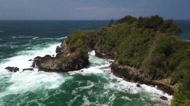 İnsansız hava aracı görüntüsü Gebyuran Sahili 'ndeki Tanjung Karang Penganten güzelliği veya Lampon Sahili, Kebumen, Central Java, Endonezya, güzel mercan kayalıkları, sakin dalgalar, tepeler ve yeşil ağaçlarla dolu bir sahil.