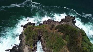 İnsansız hava aracı görüntüsü Gebyuran Sahili 'ndeki Tanjung Karang Penganten güzelliği veya Lampon Sahili, Kebumen, Central Java, Endonezya, güzel mercan kayalıkları, sakin dalgalar, tepeler ve yeşil ağaçlarla dolu bir sahil.