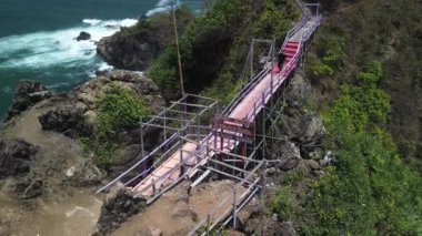 İnsansız hava aracı görüntüsü Gebyuran Sahili 'ndeki Tanjung Karang Penganten güzelliği veya Lampon Sahili, Kebumen, Central Java, Endonezya, güzel mercan kayalıkları, sakin dalgalar, tepeler ve yeşil ağaçlarla dolu bir sahil.