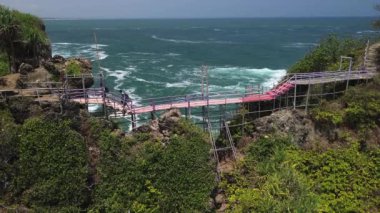 İnsansız hava aracı görüntüsü Gebyuran Sahili 'ndeki Tanjung Karang Penganten güzelliği veya Lampon Sahili, Kebumen, Central Java, Endonezya, güzel mercan kayalıkları, sakin dalgalar, tepeler ve yeşil ağaçlarla dolu bir sahil.