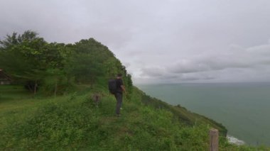 Bir adam sahildeki platforma doğru yürür ve Bukit Jerit Kebumen 'deki deniz manzarasına bakar.