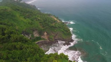 İnsansız hava aracı, Bukit Jerit Kebumen Central Java Endonezya 'daki deniz kıyılarını dalga ve mercan resifleriyle çevreleyen yeşil tepeleri görüyor.