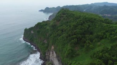 İnsansız hava aracı, Bukit Jerit Kebumen Central Java Endonezya 'daki deniz kıyılarını dalga ve mercan resifleriyle çevreleyen yeşil tepeleri görüyor.
