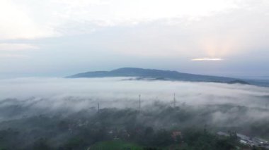 Dağların hava aracı görüntüsü ve sabah sisi kırsal bölgeyi kaplıyor.