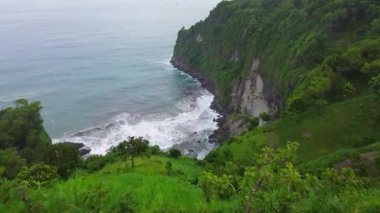 Jerit Hill Kebumen 'de, dalgalarla, mercan resifleriyle ve kayalarla çevrili deniz kenarları ve yeşil ağaçlarla dikilen bir adamın hava aracı görüntüsü. 
