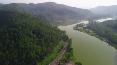 Serayu Nehri Barajı 'nın hava aracı görüntüsü. Arkasında tepeler ve ağaçlar olan yollar, trafik ve demiryolları var.