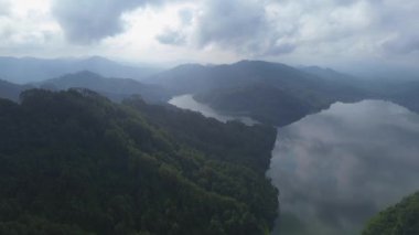 Sabahları sisli olan Sempor Reservoir Nehri 'nin arka plandaki tepeler ve ağaçlarla insansız hava aracı görüntüsü.
