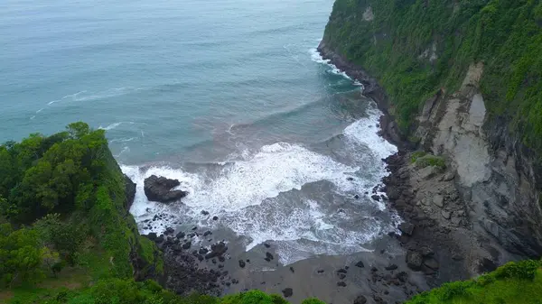 Jerit Hill Kebumen Endonezya 'nın insansız hava aracı manzarası, güzel tepeleri, yeşil ağaçları, mercan kayaları, dalgaları ve okyanusları olan deniz kıyısı.