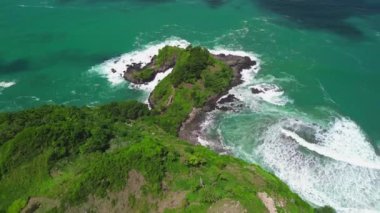 Uçağı, tepeler, yeşil ağaçlar, mercanlar ve Endonezya 'daki okyanustan gelen dalgalarla kıyı şeridini gösteriyor.