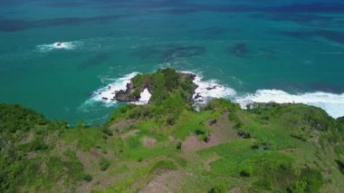 Lampon Beach Kebumen Central Java Endonezya 'daki tepeler, yeşil ağaçlar, mercanlar ve okyanustan gelen dalgalarla hava aracı görüntüsü.