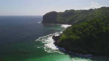 Sawangan plajı Kebumen Central Java Endonezya 'daki tepeler, yeşil ağaçlar, mercan, sahil kumu ve okyanus dalgalarıyla kıyı şeridinin güzelliğini gösteren hava aracı görüntüsü.