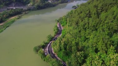 Serayu Nehri, Banyumas, Central Java, Endonezya kıyılarındaki ağaç ve tepelerden oluşan otobanın insansız hava aracı görüntüsü