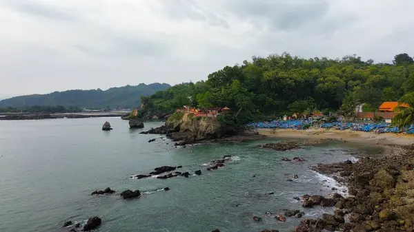 Tepeleri ve ağaçları olan kıyı şeridinin hava aracı görüntüsü, aynı zamanda mercan kayalıkları ve deniz manzarası Pedalen Sahili Kebumen Merkezi Java Endonezya 'daki deniz dalgaları.