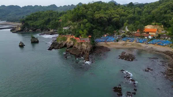 Tepeleri ve ağaçları olan kıyı şeridinin hava aracı görüntüsü, aynı zamanda mercan kayalıkları ve deniz manzarası Pedalen Sahili Kebumen Merkezi Java Endonezya 'daki deniz dalgaları.