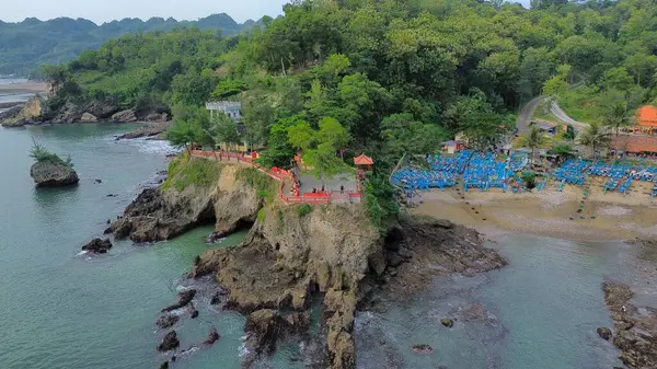 Tepeleri ve ağaçları olan kıyı şeridinin hava aracı görüntüsü, aynı zamanda mercan kayalıkları ve deniz manzarası Pedalen Sahili Kebumen Merkezi Java Endonezya 'daki deniz dalgaları.