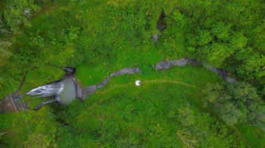 Curug Gong Banyumas Merkez Java Endonezya 'nın insansız hava aracı görüntüsü, bitki örtüsü ve ormanın ortasında yeşil ağaçlar arasında bir şelale.