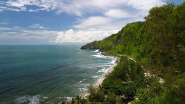 Tepeleri ve ağaçları olan kıyı şeridinin hava aracı görüntüsü, aynı zamanda mercan kayalıkları ve okyanus manzarası Menganti Beach Kebumen Central Java Endonezya 'da.