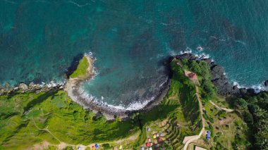 Aerial drone view of coastline with hills and trees, as well as view of coral cliffs and sea with waves from the ocean in Menganti Beach Kebumen Central Java Indonesia clipart