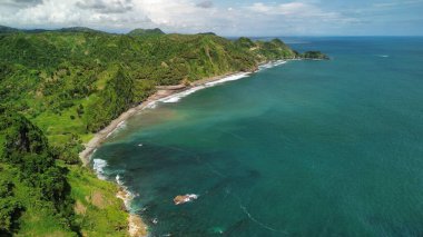 Tepeleri ve ağaçları olan kıyı şeridinin hava aracı görüntüsü, aynı zamanda mercan kayalıkları ve okyanus manzarası Menganti Beach Kebumen Central Java Endonezya 'da.