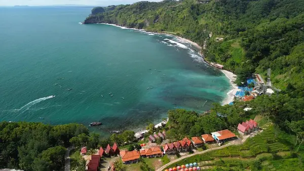 Tepeleri ve ağaçları olan kıyı şeridinin hava aracı görüntüsü, aynı zamanda mercan kayalıkları ve okyanus manzarası Menganti Beach Kebumen Central Java Endonezya 'da.