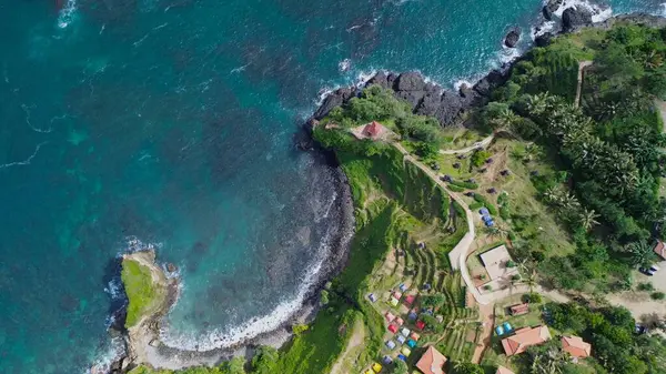 Tepeleri ve ağaçları olan kıyı şeridinin hava aracı görüntüsü, aynı zamanda mercan kayalıkları ve okyanus manzarası Menganti Beach Kebumen Central Java Endonezya 'da.