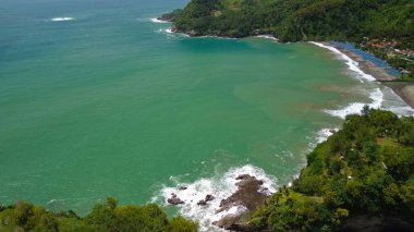 Aerial drone view of coastline with hills and trees, as well as view of coral cliffs and sea with waves from the ocean in Watu Bale Beach Kebumen Central Java Indonesia clipart