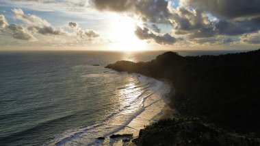 Tepeler ve ağaçlarla kıyı şeridini gösteren hava aracı manzarası, Watu Bale Beach Kebumen Central Java Endonezya 'daki mercan kayalıkları ve deniz dalgaları.