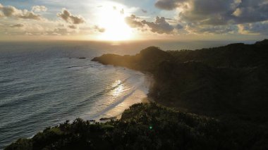 Aerial drone view of coastline with hills and trees, as well as view of coral cliffs and sea with waves from the ocean in Watu Bale Beach Kebumen Central Java Indonesia clipart