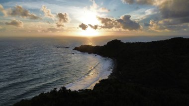 Tepeler ve ağaçlarla kıyı şeridini gösteren hava aracı manzarası, Watu Bale Beach Kebumen Central Java Endonezya 'daki mercan kayalıkları ve deniz dalgaları.