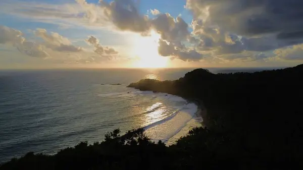 Tepeler ve ağaçlarla kıyı şeridini gösteren hava aracı manzarası, Watu Bale Beach Kebumen Central Java Endonezya 'daki mercan kayalıkları ve deniz dalgaları.