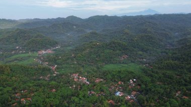 Tepeleri ve ağaçları olan kıyı şeridinin hava aracı görüntüsü, Sagara manzarasında okyanus dalgaları olan mercan kayalıkları ve deniz manzarası, Karang Bolong Beach Kebumen Merkezi Java Endonezya olarak da bilinir.