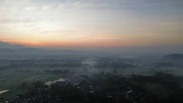 Pirinç tarlalarının ve kırsal alanların insansız hava aracı görüntüsü. Dağların arka planı, güneş doğuşu ve sabah bulutları.