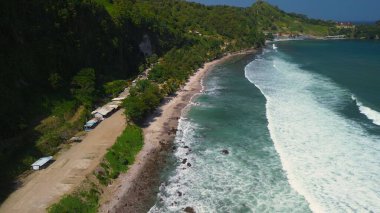  Tepelerin, kayalıkların, ağaçların, kumsalların ve Menganti Sahili, Kebumen, Central Java, Endonezya 'nın deniz ve okyanuslarından gelen dalgaların bulunduğu bir adam.