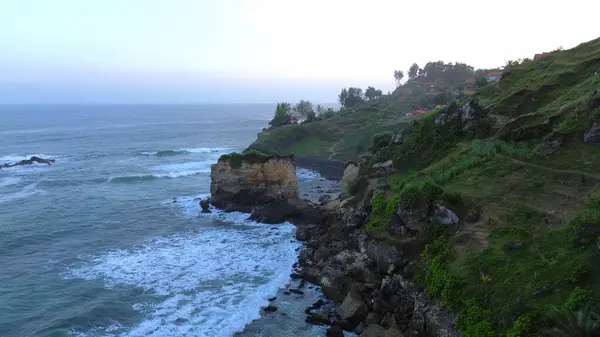  Tepelerin, kayalıkların, ağaçların, kumsalların ve Menganti Sahili, Kebumen, Central Java, Endonezya 'nın deniz ve okyanuslarından gelen dalgaların bulunduğu bir adam.