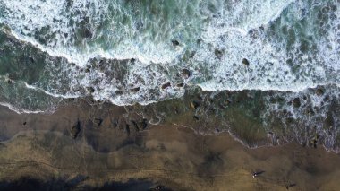 Tepeler ve ağaçlarla dolu kıyı şeridinin hava aracı görüntüsü, mercan kayalıkları ve deniz manzarası, Pecaron Beach Kebumen Central Java Endonezya 'daki okyanus dalgaları.