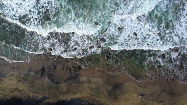 Tepeler ve ağaçlarla dolu kıyı şeridinin hava aracı görüntüsü, mercan kayalıkları ve deniz manzarası, Pecaron Beach Kebumen Central Java Endonezya 'daki okyanus dalgaları.