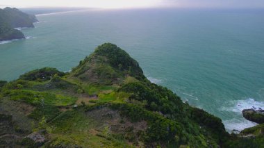 Tepeler, ağaçlar, kayalıklar, mercan resifleri ve Surumanis Sahili, Kebumen, Central Java 'daki denizden gelen dalgalarla birlikte kuş bakışı kıyı şeridi manzarası