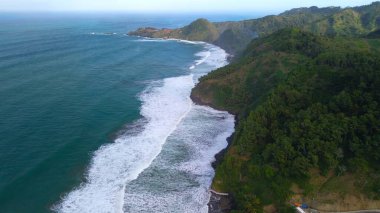 Tepeler, ağaçlar, kayalıklar, mercan resifleri ve Surumanis Sahili, Kebumen, Central Java 'daki denizden gelen dalgalarla birlikte kuş bakışı kıyı şeridi manzarası