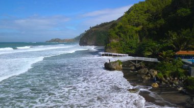 Tepeler, ağaçlar, kayalıklar, mercan resifleri ve Surumanis Sahili, Kebumen, Central Java 'daki denizden gelen dalgalarla birlikte kuş bakışı kıyı şeridi manzarası