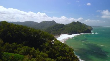 Tepeler, ağaçlar, kayalıklar, mercan resifleri ve Surumanis Sahili, Kebumen, Central Java 'daki denizden gelen dalgalarla birlikte kuş bakışı kıyı şeridi manzarası